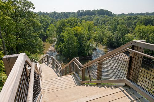 arafed wooden stairs leading down to a river and a forest, a stock photo inspired by Balcomb Greene, shutterstock contest winner, environmental art, cahaba river alabama, bentonville arkansas, outdoor staircase